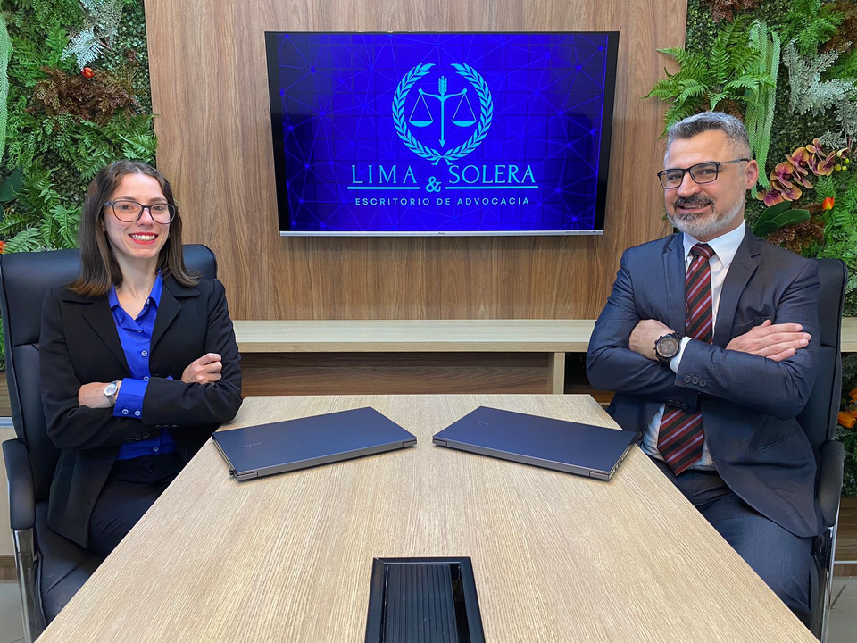 advogado trabalhista e advogada previdenciarista em frente a mesa da sala de reuniões